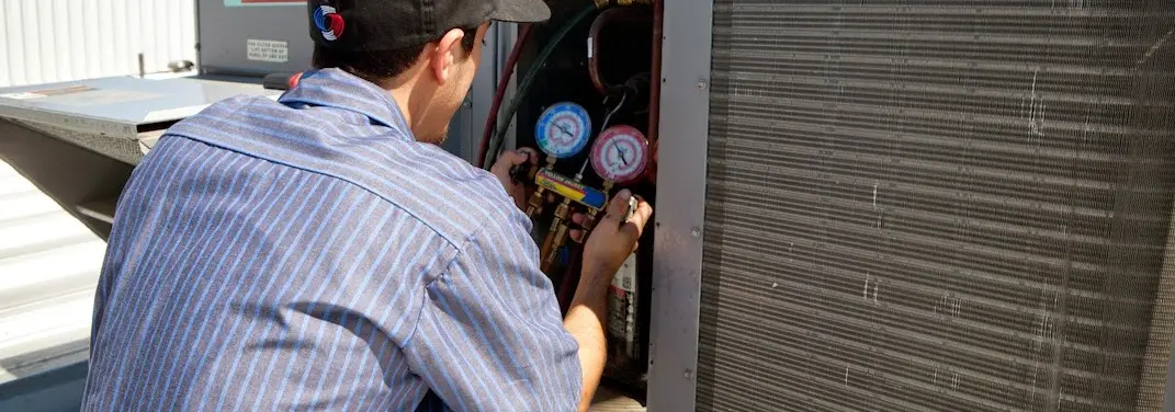 HVAC technician servicing a condenser unit in Tucker