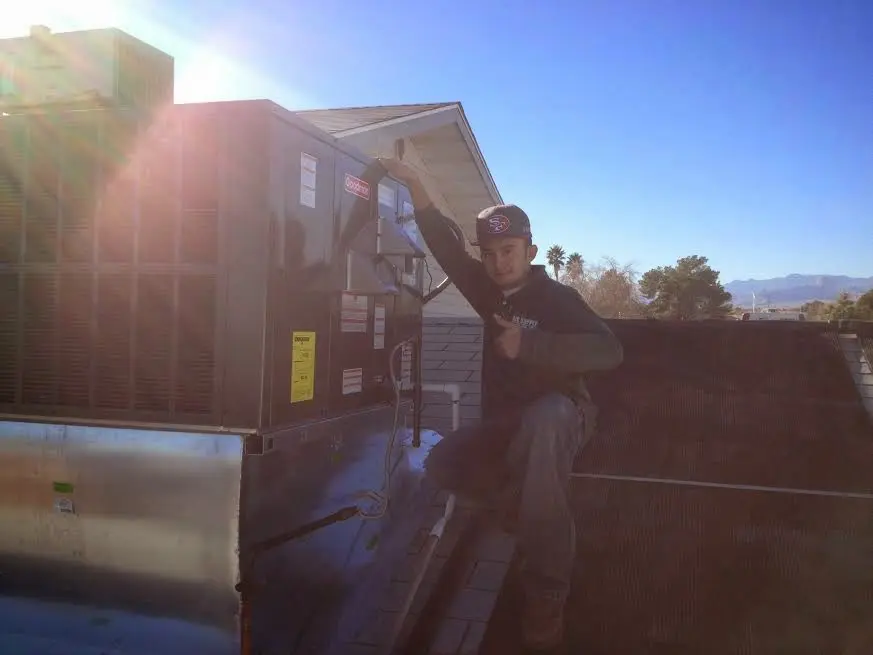 HVAC technician performing Air Duct Cleaning on a rooftop unit in Tucker